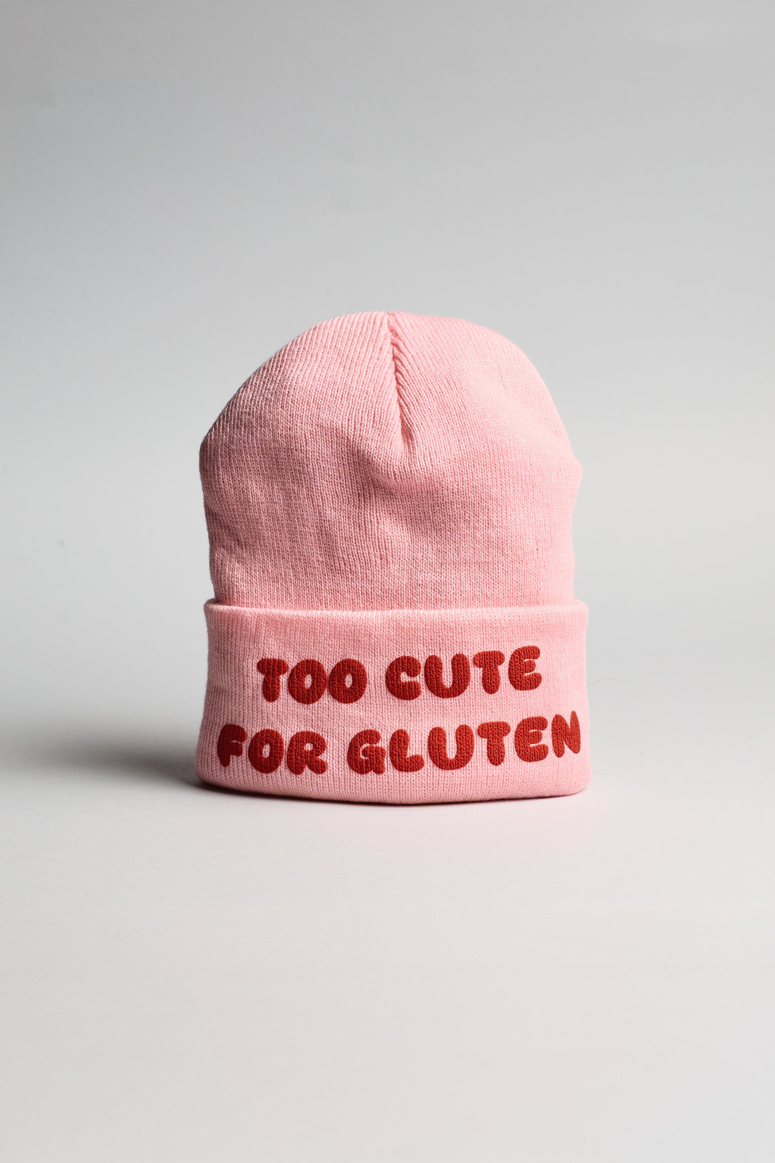 Růžová zimní čepice s červeným nápisem "too cute for gluten"